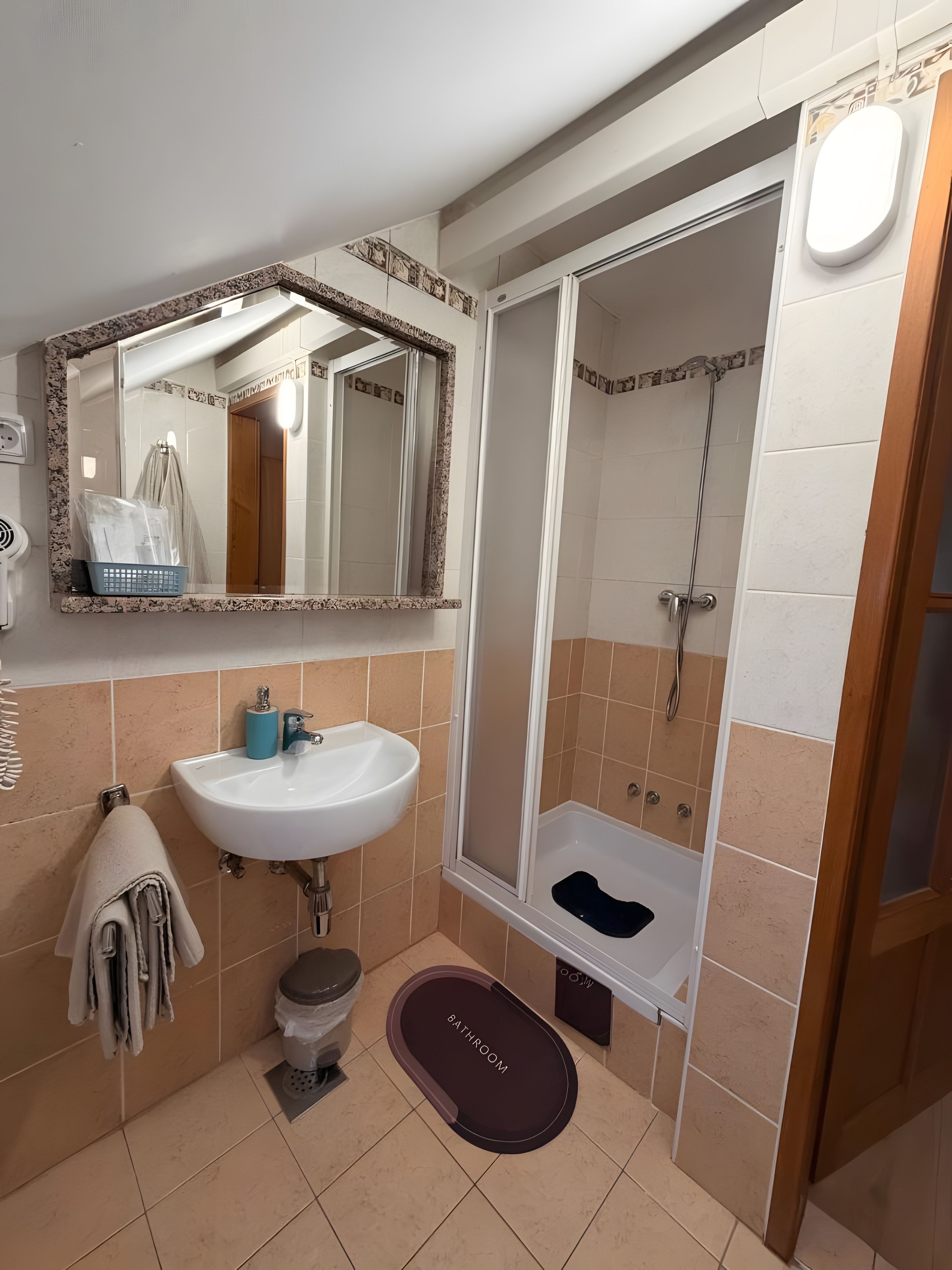 A bathroom with a sink, mirror, shower, and a towel rack.