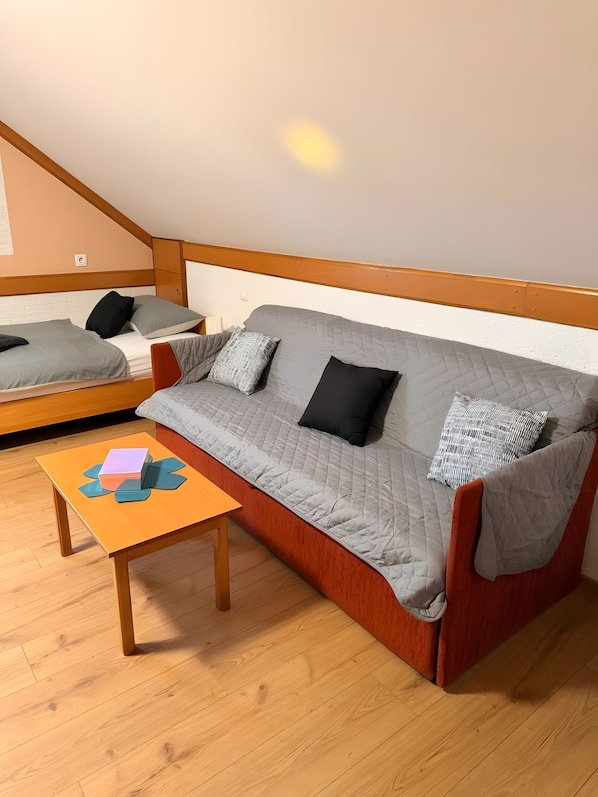Una habitación con sofá, una mesita y suelo de madera.