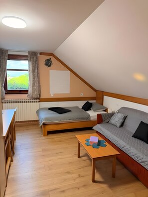Una habitación con cama tipo litera, un sofá, una mesita y una ventana con cortinas.