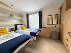 A hotel room with two beds, a window with curtains, a bedside table with a lamp, a mirror, and a wardrobe. - Boutique Lodge (Exeter)