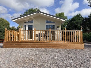 A two-story wooden house with a deck, a garage, and a large window. - Boutique Lodge (Exeter)