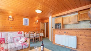 A cozy cabin interior with a dining area, a sofa, and a kitchen with wooden cabinets. - Apartment 'K2' with Mountain View and Private Terrace (Bonneval-sur-Arc)