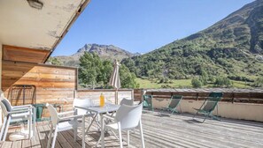 A wooden deck with outdoor furniture, a table, and chairs, overlooking a mountainous landscape. - Apartment 'K2' with Mountain View and Private Terrace (Bonneval-sur-Arc)