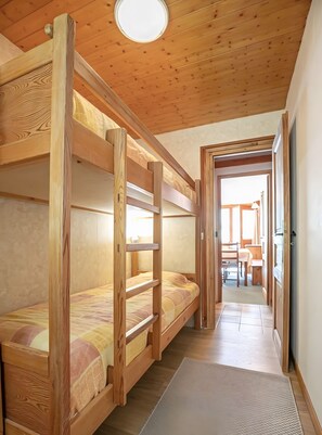 Camera con letto a castello, soffitto in legno e vista su una sala da pranzo.