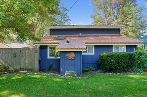 A two-story house with a blue exterior, a metal roof, and a small front porch. - Lake Thirteen Waterfront Lodge - Fire Pit & Dock (Farwell)