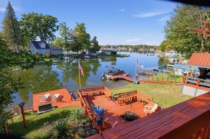 Une propriété au bord du lac, dotée d’un quai, de bateaux et d’une terrasse en bois avec des chaises.