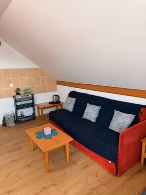 A cozy living room with a sofa, a small table, and a shelf with kitchenware. - Apartment 'Baroko Rooms Apartments' with Wi-Fi and air conditioning (Varaždin)
