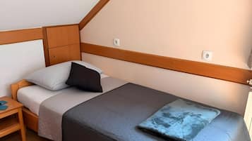 A bedroom with a bed, bedside table, and a wall-mounted light fixture.