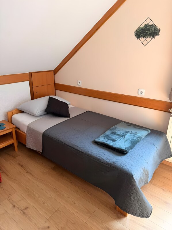 Een slaapkamer met een bed, nachtkastje en een wandlamp.