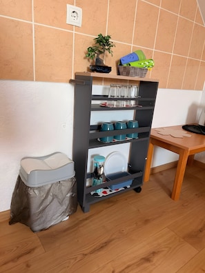 A kitchen area with a grey storage unit, a wooden table, and a trash bin. - Apartment 'Baroko Rooms Apartments' with Wi-Fi and air conditioning (Varaždin)