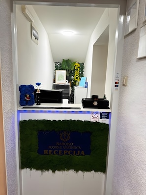 Een receptiebalie met een bordje met de tekst 'Baroko Rooms & Apartments Receptie'.