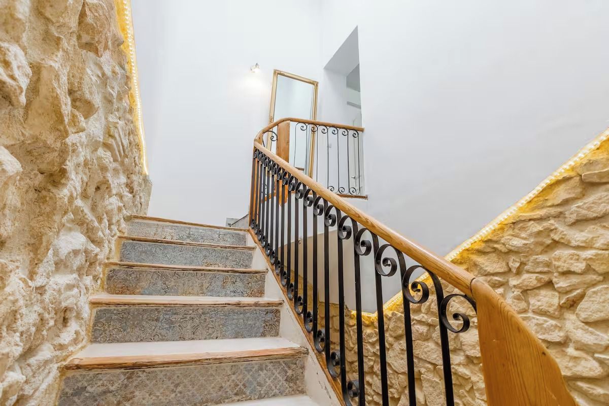 Eine Treppe mit Steinwänden und einem hölzernen Geländer.