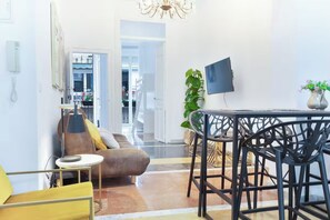 A modern living room with a sofa, a dining table with chairs, a TV, and a plant. - Casa Alicantina by Fidalsa (Alicante)