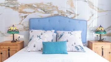 Quarto com uma cama, duas mesas de cabeceira, duas luminárias e uma parede com padrão marmorizado.