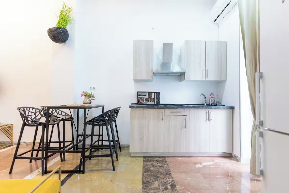 Una cocina compacta con comedor, que incluye una pequeña isla, taburetes de bar y un microondas.