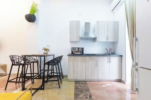 A compact kitchen with a dining area, featuring a small island, bar stools, and a microwave.