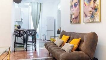Una sala de estar con un sofá marrón, dos cojines amarillos y un comedor con mesa y sillas.