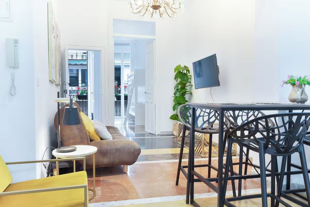 Un salon moderne avec un canapé, une table à manger et des chaises, un téléviseur et une plante.