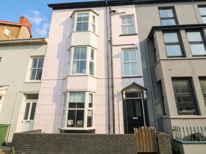 A multi-story residential building with a flat facade, a black front door, and a small balcony. - Y Glyn (Borth)