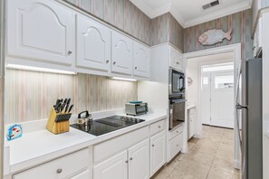 A kitchen with white cabinetry, a toaster, a kettle, and a knife block. - Pier House – Walk to Everything, Worry About Nothing (St Simons Island)