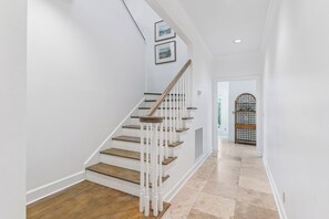 Eine Treppe mit Holzstufen und weißen Geländern, die zu einer Tür mit Glasfenster führt.