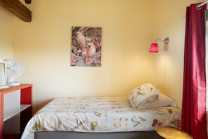 A bedroom with a bed, a bedside table, a fan, a wall-mounted lamp, and a red curtain. - Apartment 'Gîte Du Jardin - Domaine Les Bois' with Wi-Fi (Sixt-sur-Aff)