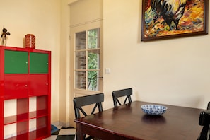 A dining area with a wooden table, two chairs, a red and green cabinet, and a painting on the wall. - Apartment 'Gîte Du Jardin - Domaine Les Bois' with Wi-Fi (Sixt-sur-Aff)