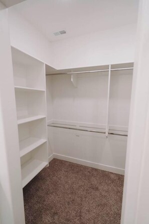 A closet with white shelving and a brown carpeted floor. - Bright 2-Bedroom Home with Mountain Views (Hyrum)