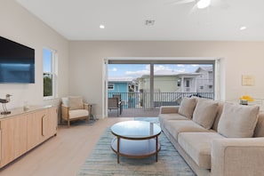 A spacious living room with a large sofa, a coffee table, and a TV mounted on the wall. - 🌴Sandpiper Shores | Heated Pool + Steps to Beach 🌴 (Fort Myers Beach)