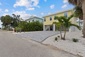 A residential area with two houses, a paved driveway, and a palm tree. - 🌴Sandpiper Shores | Heated Pool + Steps to Beach 🌴 (Fort Myers Beach)
