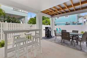 An outdoor patio with a grill, seating, and a view of a pool. - 🌴Sandpiper Shores | Heated Pool + Steps to Beach 🌴 (Fort Myers Beach)