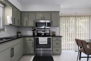 Een moderne keuken met een roestvrijstalen oven, magnetron en een zwart aanrecht.