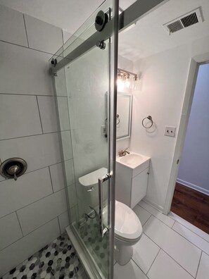 A modern bathroom with a glass-enclosed shower, a white sink, and a toilet. - Modern Capitol Hill 1BR - Walk to H Street, Metro & Union Station  Unit 3 (Washington)