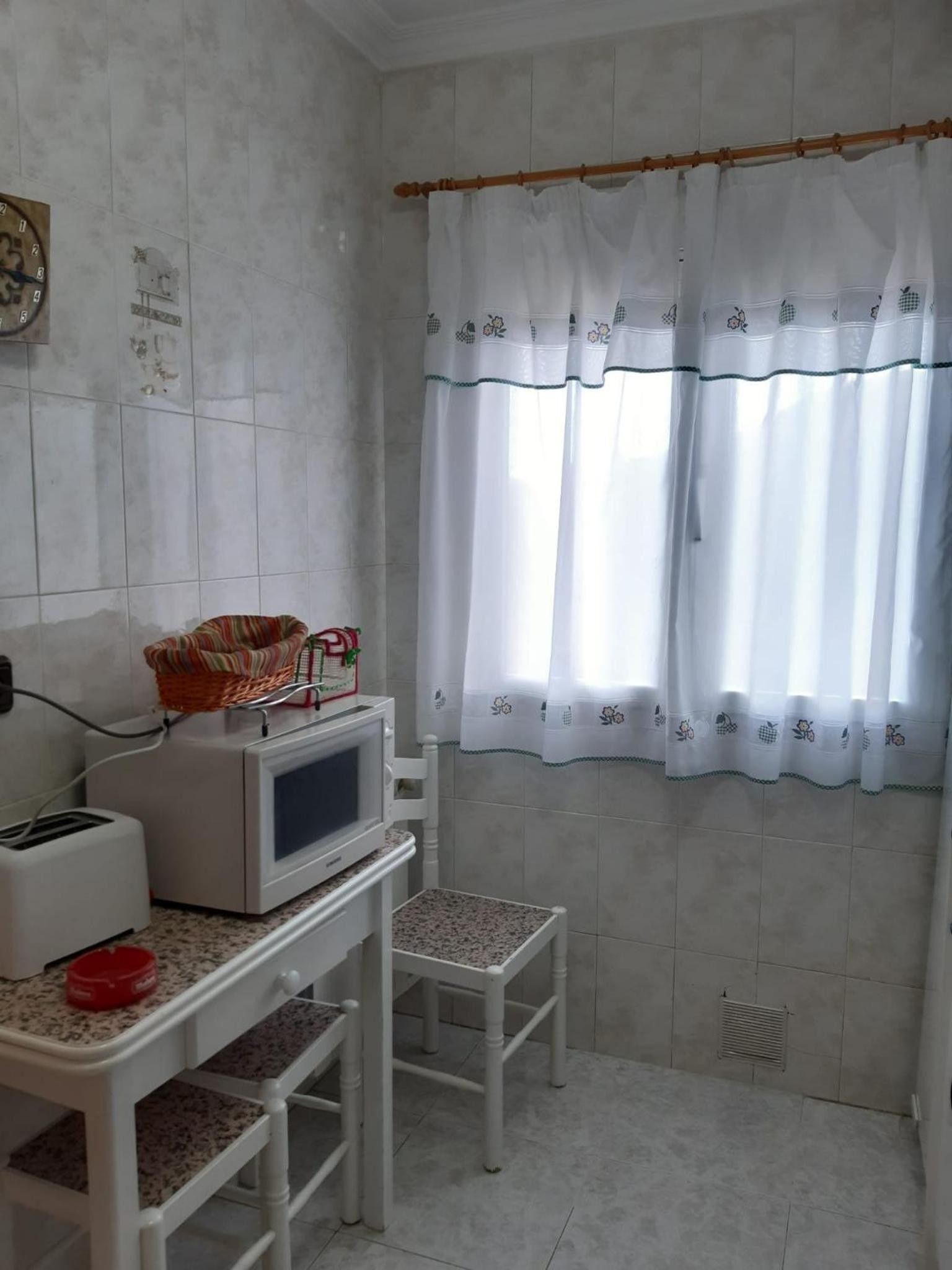 Una pequeña kitchenette con microondas, tostadora y una cesta en la encimera.