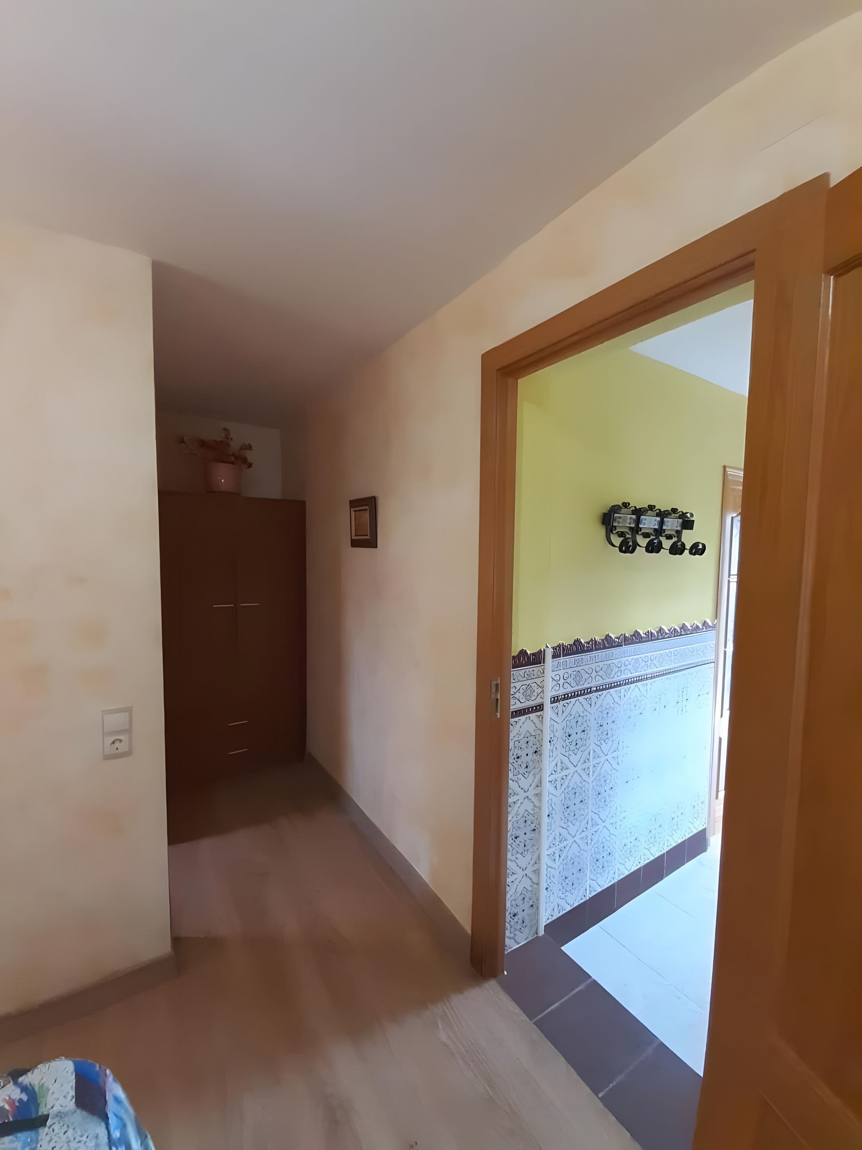 Un couloir avec une porte en bois donnant sur un balcon dont le sol est recouvert de carreaux décoratifs.
