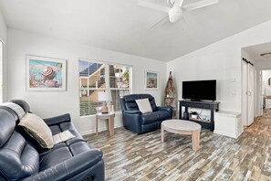 A modern living room with a leather sofa, a blue armchair, and a wooden coffee table. - The Salty Dog Golf Cart Ocean Lakes (Horry County)