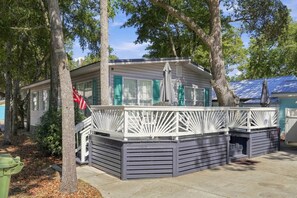 A small house with a porch, a flag, and a covered outdoor seating area. - The Salty Dog Golf Cart Ocean Lakes (Horry County)