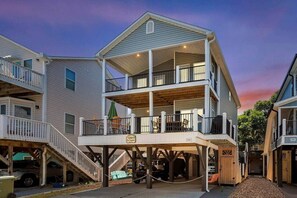 A multi-story building with a covered outdoor area, wooden deck, and a sign indicating a restaurant. - Seas the Day Retreat | GolfCart, LazyRiver & Beach (Horry County)