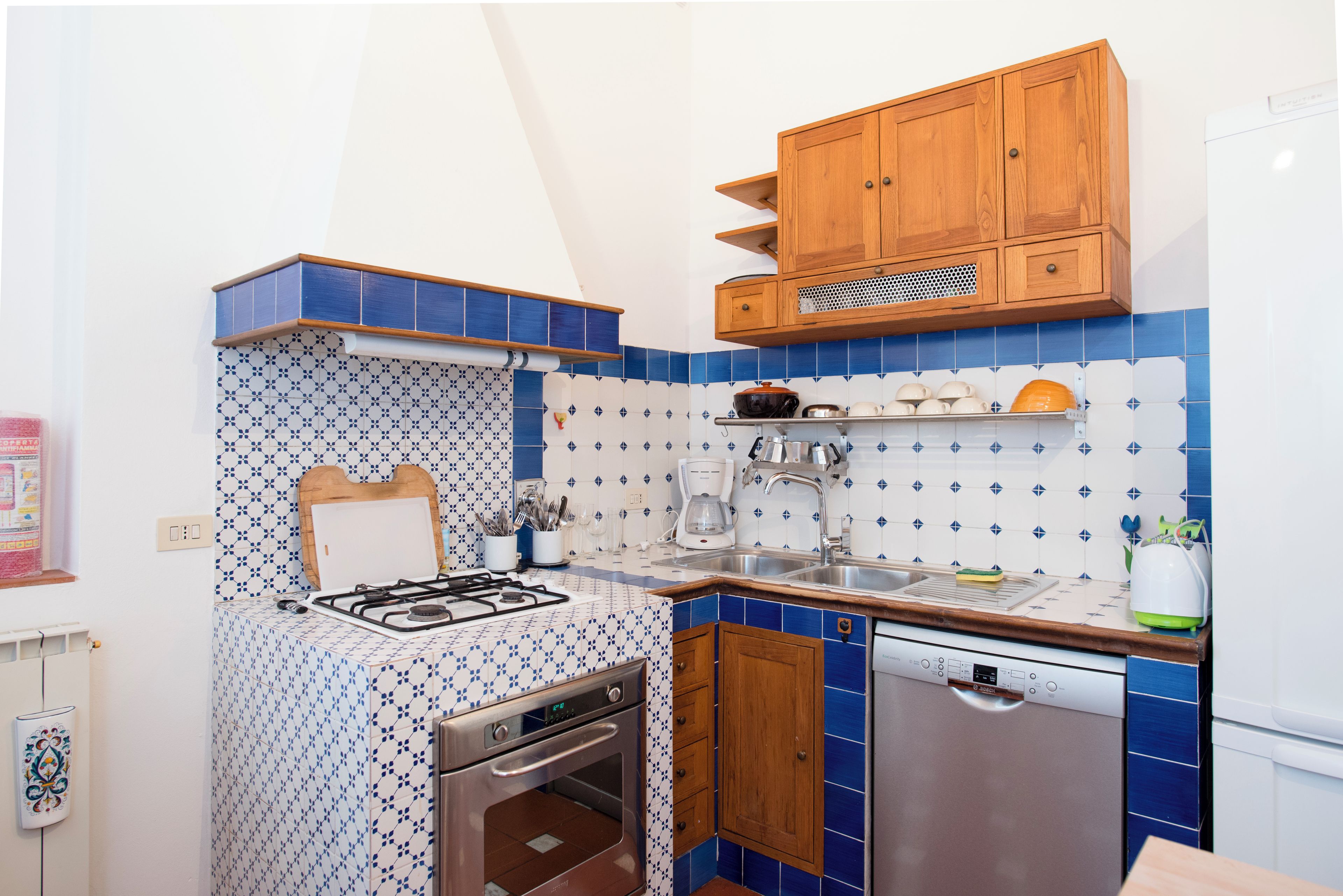 Une cuisine de taille réduite équipée d’une cuisinière à gaz, d’un four, d’un évier et de meubles de rangement en bois.