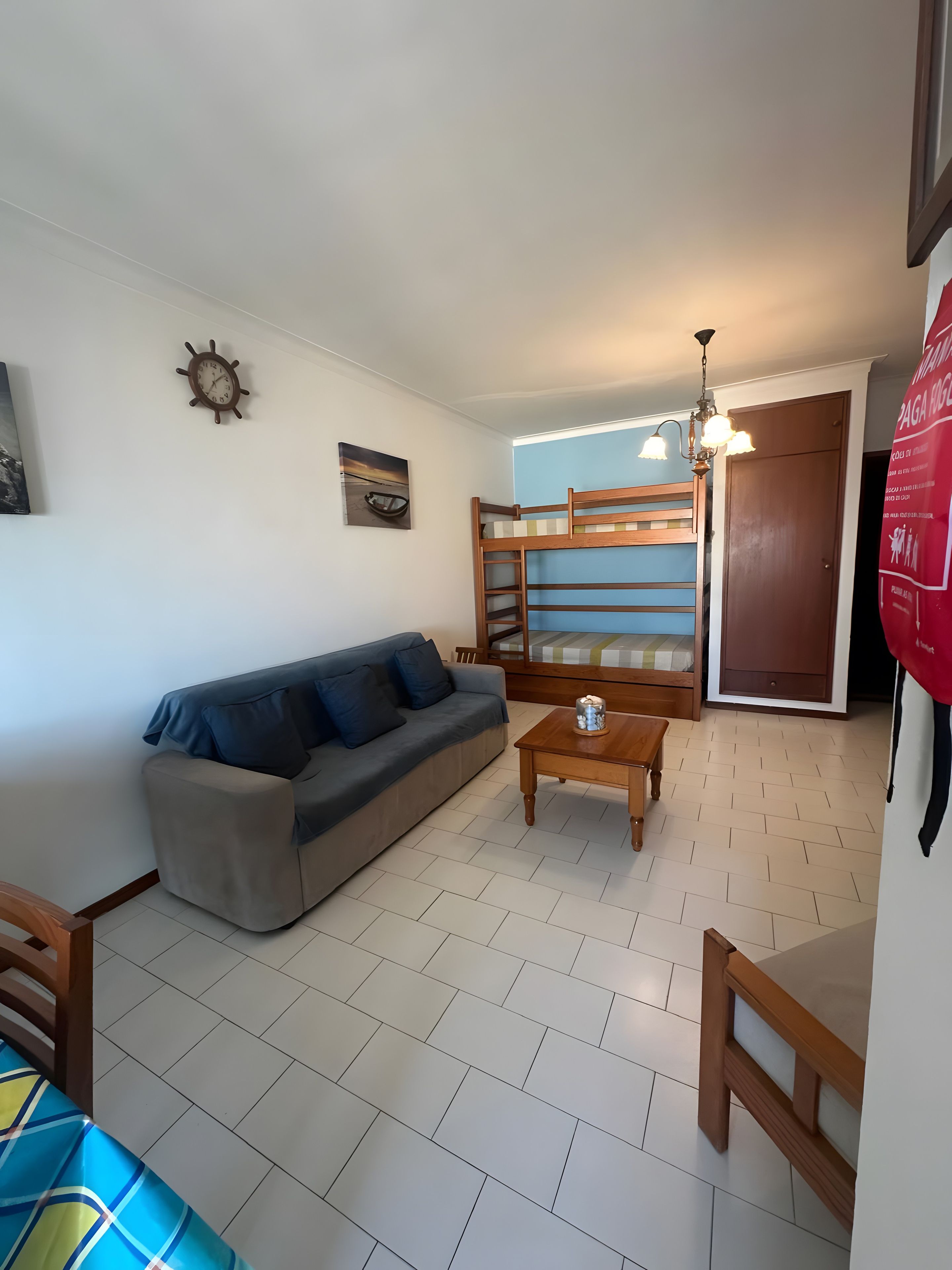Ein Wohnzimmer mit einer Couch, einem Couchtisch, einer Holzbank, einer Tür und einer an der Wand befestigten Uhr.