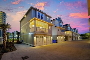 Een rij twee verdiepingen tellende huizen met aangesloten garages, een overdekte gang en een aangelegde tuin.