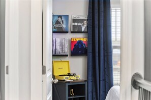 Een kamer met een bed, een klein tafeltje met een geel voorwerp, en wanddecoratie inclusief een poster met de tekst 'STARBOY'.