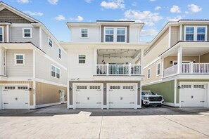 Un immeuble résidentiel à plusieurs étages, doté de garages à deux niveaux et d’un balcon.