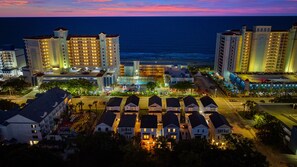 Un hotel frente al mar con varios edificios altos, un estacionamiento y vistas a la playa.