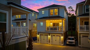 A two-story residential building with a balcony, multiple garage doors, and a driveway. - HGTV-Featured Beach House w/ Glow Arcade (Myrtle Beach)