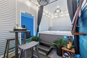 A room with a large bed, a small table with a basket, a bench, and a heater. - Themed Beach House · Private Hot Tub · Neon Arcade (Myrtle Beach)