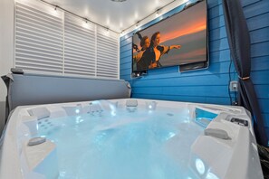 A hot tub with a television mounted on the wall displaying a movie scene. - Themed Beach House · Private Hot Tub · Neon Arcade (Myrtle Beach)