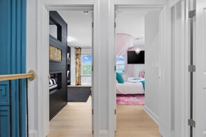 Ein Flur, der zu einem Schlafzimmer mit Bett, Fernseher und einem blickdichten Fenster führt.