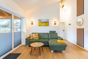 A modern living room with a sectional sofa, a small round table, and a painting on the wall. - Ferienhaus mit Eigener Sauna und Schoener Terrasse (Toenning)