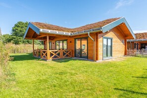 A wooden cabin with a covered patio and large windows. - Ferienhaus mit Eigener Sauna und Schoener Terrasse (Toenning)